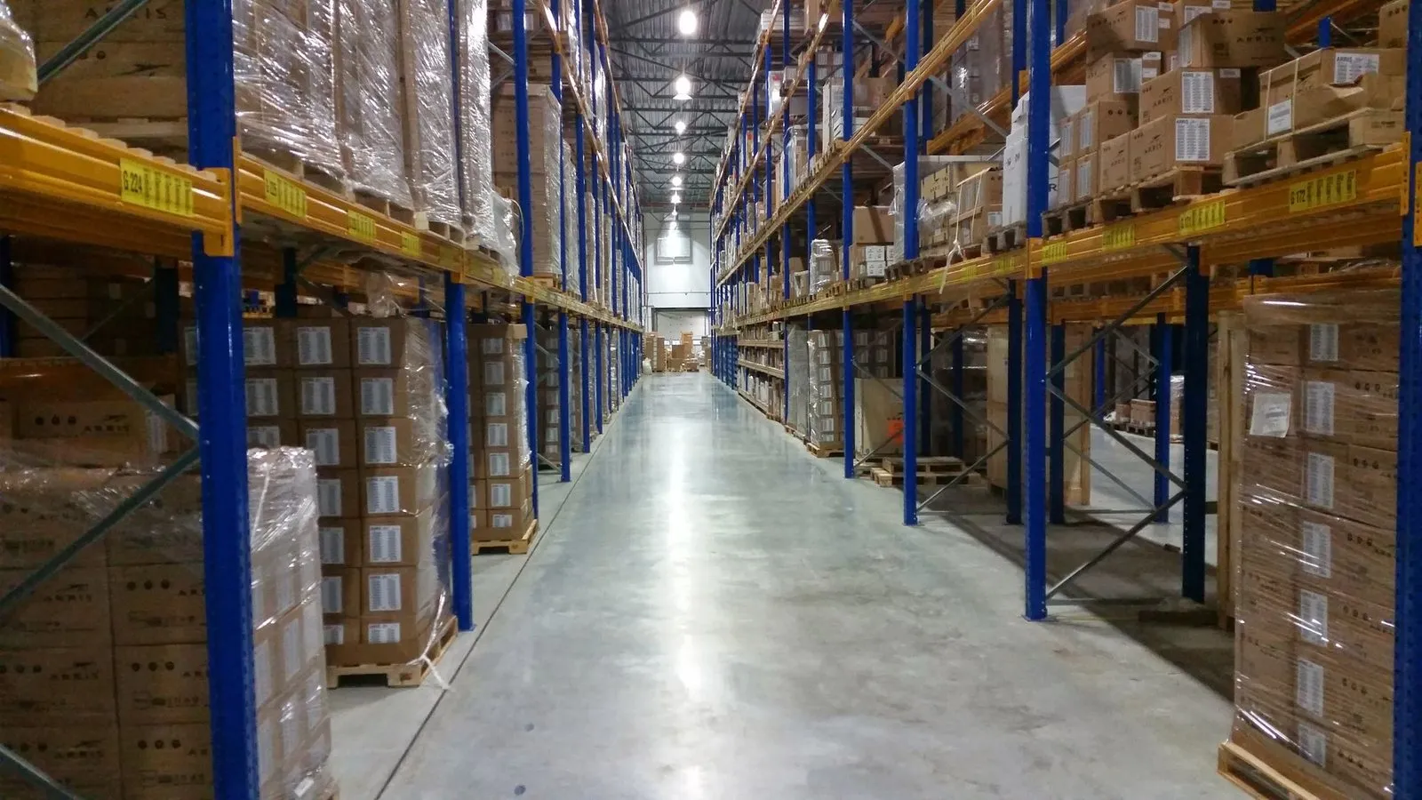 Allée d’entrepôt, palettes filmées stockées sur racks